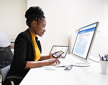 Frau arbeitet mit Handy und Laptop