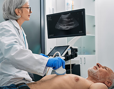 Ärztin führt Sonographie am Oberkörper eines Mannes durch