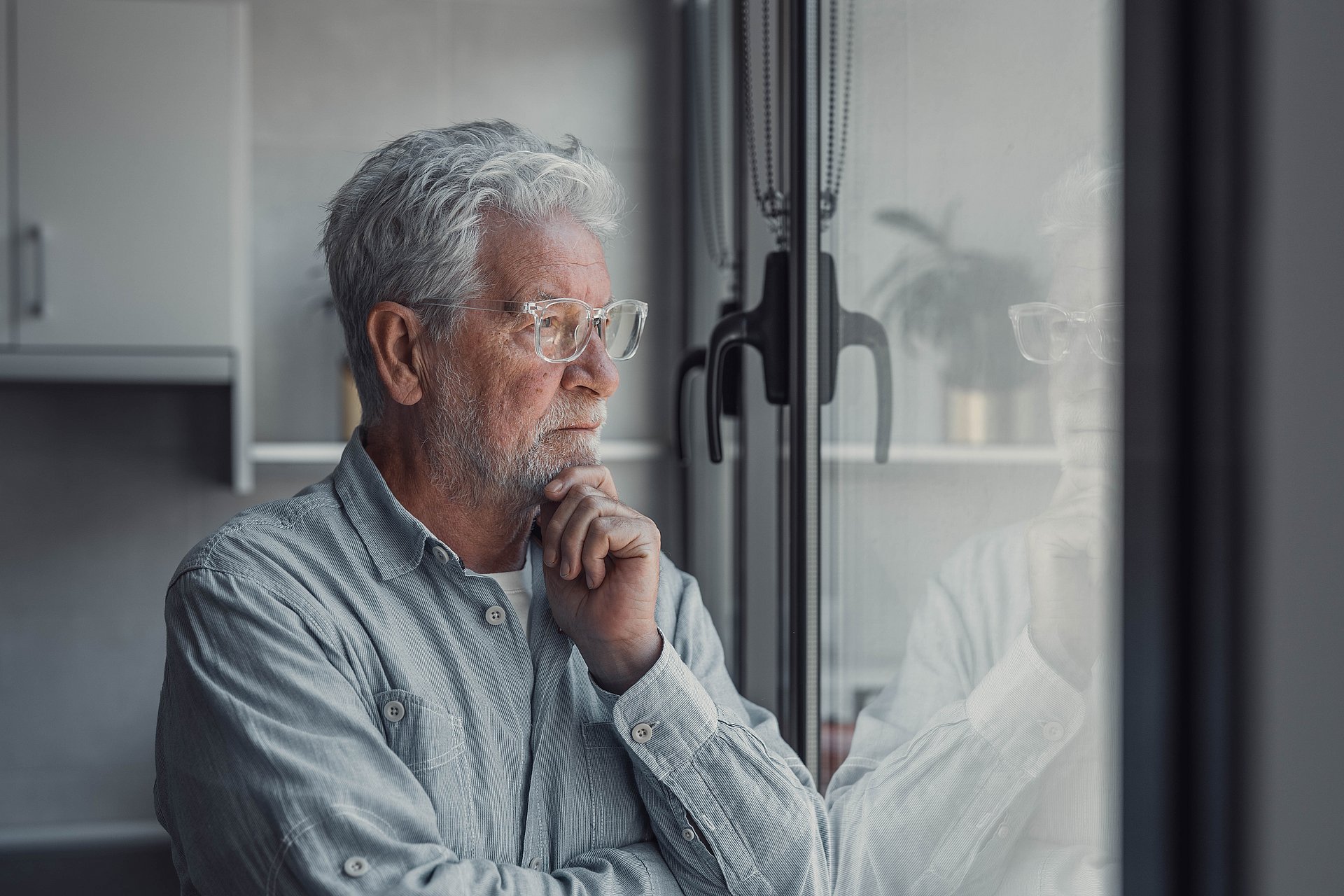 Älterer Mann schaut aus dem Fenster