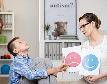 Junge wählt zwischen Lachendem und Traurigen Smiley