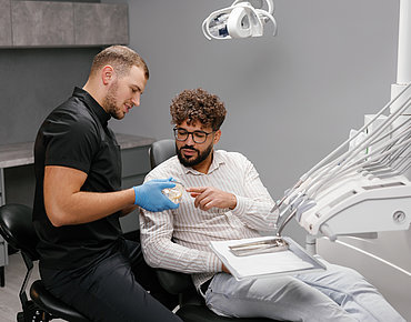 Zahnarzt erklärt Patient Aufbissbehelfe