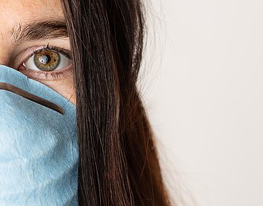 Junge Frau mit Maske hat Angst vor Corona