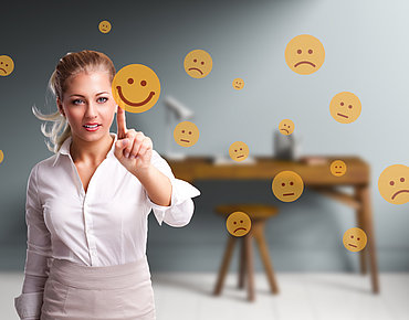 Symbolbild Kundenzufriedenheit: Frau ist umgeben von Smileys
