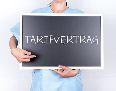Krankenpflegerin hält Schild mit Aufschrift Tarifvertrag