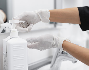 Hände betätigen einen Desinfektionsmittelspender