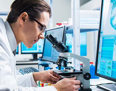 Wissenschaftler untersucht mit einem Mikroskop Affenpocken