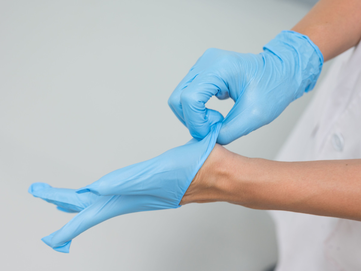 Ärztin zieht blaue Latexhandschuhe an