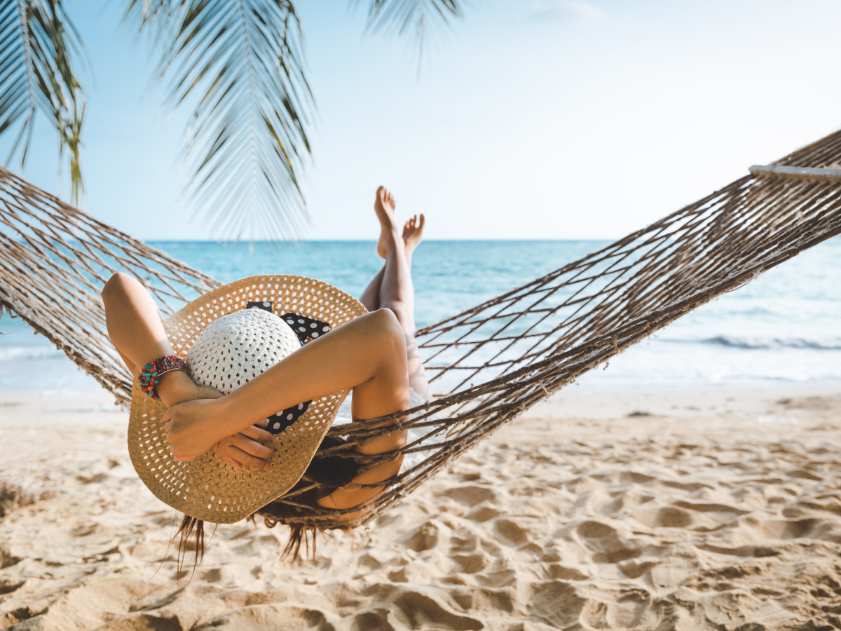 Symbolbild Urlaub: Frau liegt in Hängematte am Strand