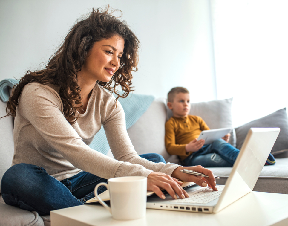 Mutter arbeitet am Laptop auf Couch